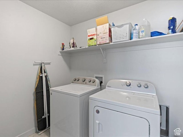 clothes washing area with washing machine and dryer, baseboards, and laundry area