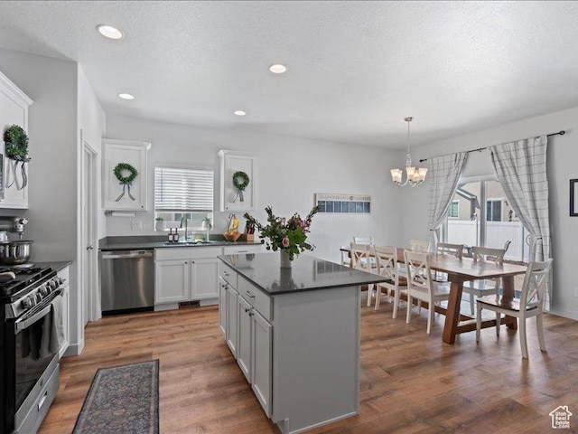 kitchen featuring stainless steel appliances, a sink, dark countertops, a chandelier, and a kitchen island