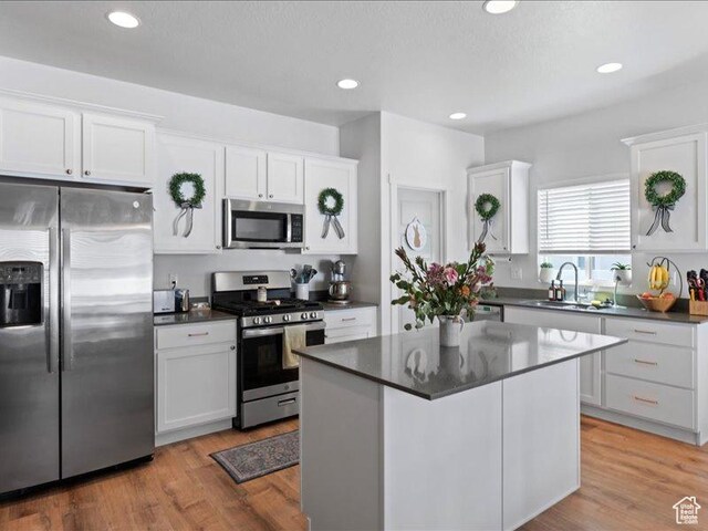 kitchen featuring dark countertops, appliances with stainless steel finishes, a sink, and white cabinets