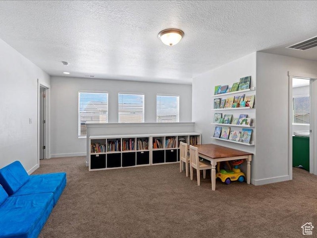 recreation room with baseboards, visible vents, carpet, and a textured ceiling