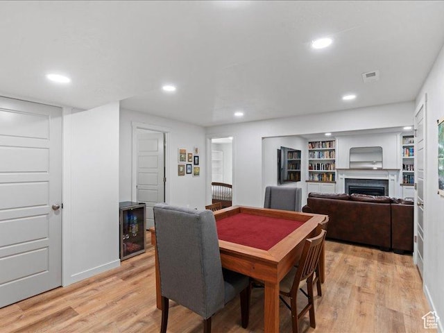 dining space featuring recessed lighting, beverage cooler, light wood finished floors, visible vents, and a fireplace