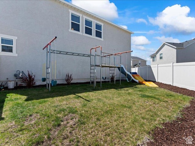back of property with a yard, a playground, and fence