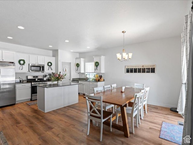 dining room with wood finished floors, recessed lighting, and a notable chandelier
