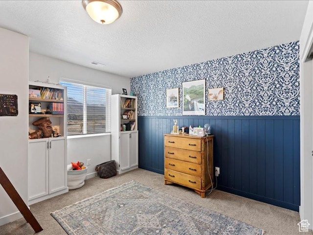 bedroom featuring wallpapered walls, carpet, and wainscoting