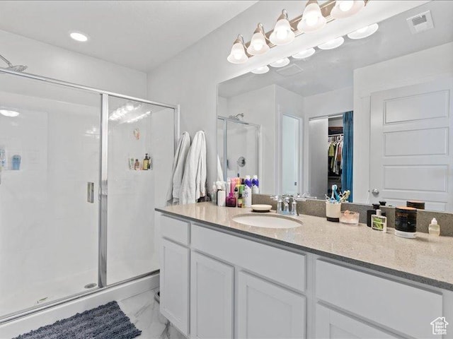full bathroom with a shower stall, a spacious closet, marble finish floor, visible vents, and vanity