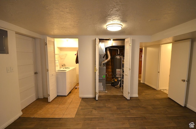 interior space featuring water heater, wood finished floors, washer and clothes dryer, and a textured ceiling