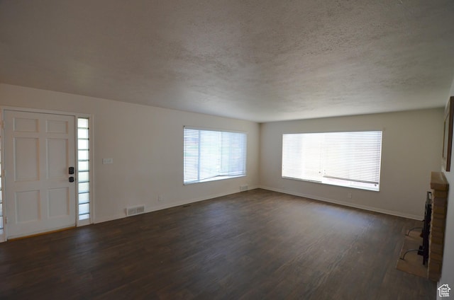 entrance foyer featuring baseboards, visible vents, a textured ceiling, and dark wood finished floors
