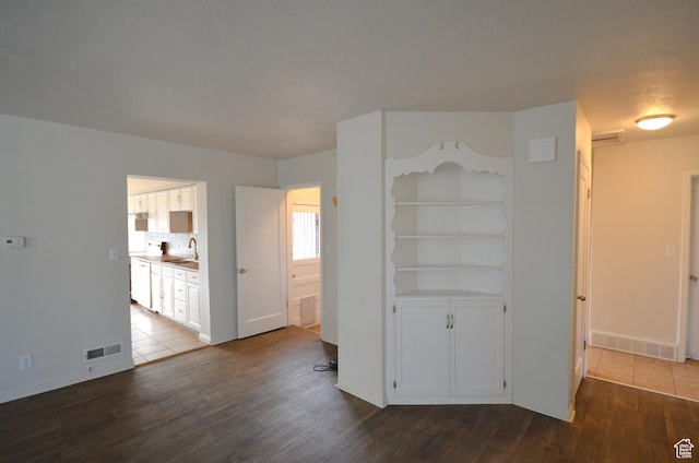 interior space with baseboards, visible vents, a sink, and dark wood-style floors