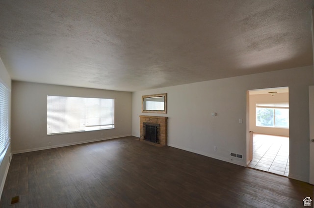 unfurnished living room featuring wood finished floors, a fireplace, visible vents, and a textured ceiling