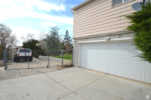 garage featuring fence, driveway, and a gate