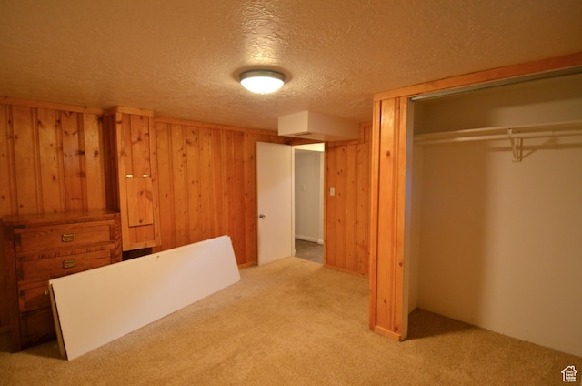 unfurnished bedroom with wood walls, a closet, a textured ceiling, and carpet