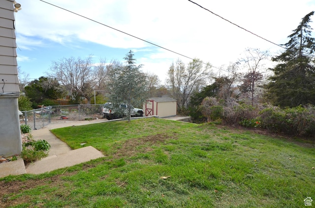 view of yard featuring fence, an outbuilding, and a shed
