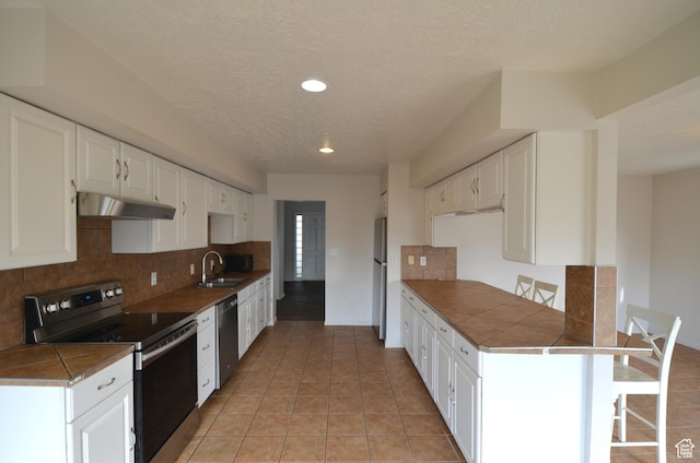 kitchen featuring decorative backsplash, under cabinet range hood, white cabinetry, and appliances with stainless steel finishes