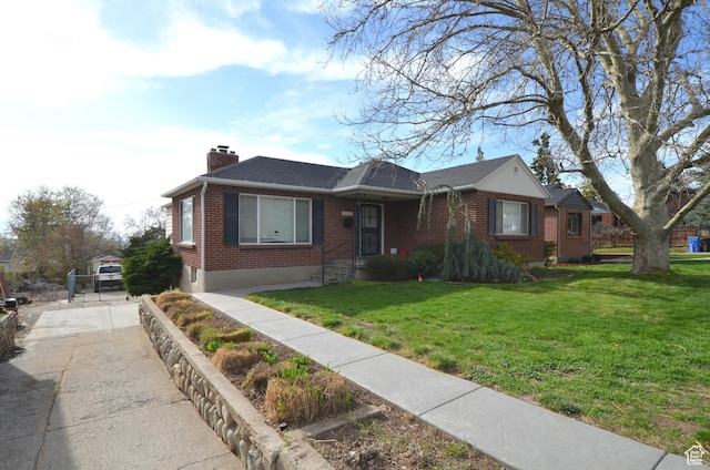 view of front of property featuring driveway, a chimney, brick siding, and a front lawn