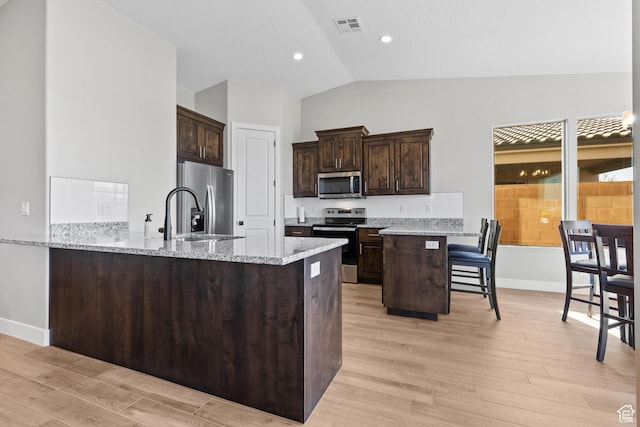315 W Camino Borde, Washington, UT 84780 - kitchen with dark brown cabinetry, stainless steel appliances, light wood-style flooring, a peninsula, and visible vents