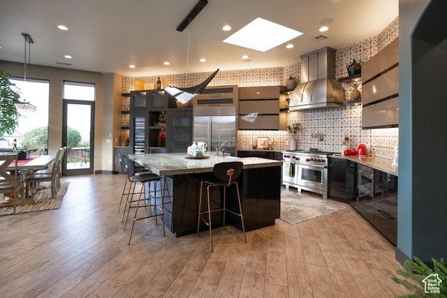 3052 N Snow Canyon Pkwy Unit 67, St George, UT 84770 - kitchen with high end appliances, light wood-style flooring, a skylight, and wall chimney range hood