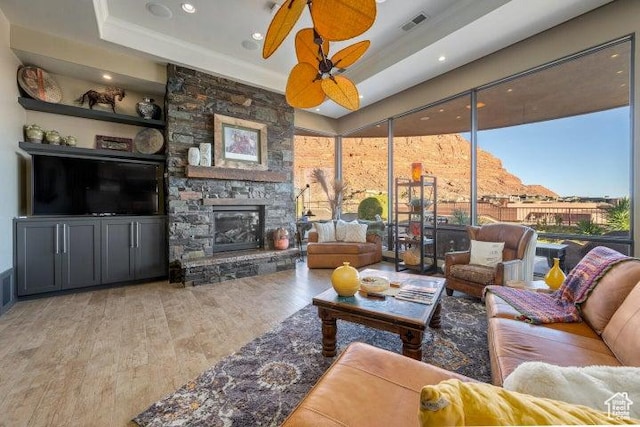 3052 N Snow Canyon Pkwy Unit 67, St George, UT 84770 - living area featuring visible vents, a ceiling fan, wood finished floors, a stone fireplace, and a raised ceiling
