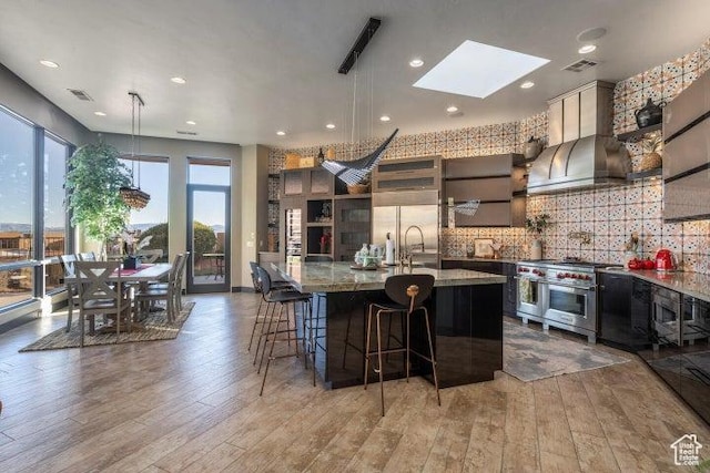 3052 N Snow Canyon Pkwy Unit 67, St George, UT 84770 - kitchen with premium appliances, a skylight, light wood-type flooring, wall chimney exhaust hood, and visible vents