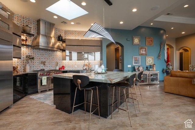 3052 N Snow Canyon Pkwy Unit 67, St George, UT 84770 - kitchen featuring wall chimney exhaust hood, arched walkways, backsplash, high end appliances, and a skylight