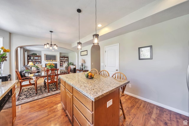 kitchen with open floor plan, light wood-type flooring, a breakfast bar area, arched walkways, and decorative light fixtures