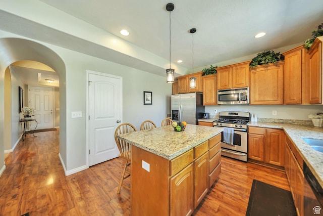 kitchen featuring a center island, wood finished floors, stainless steel appliances, and a breakfast bar area