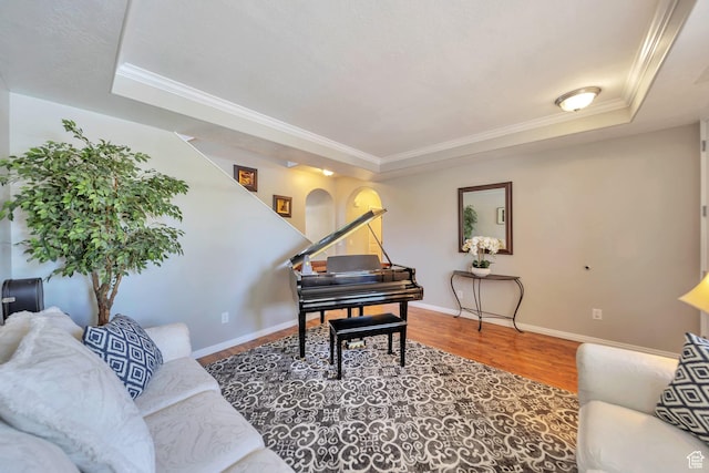 living room with wood finished floors, ornamental molding, and a raised ceiling