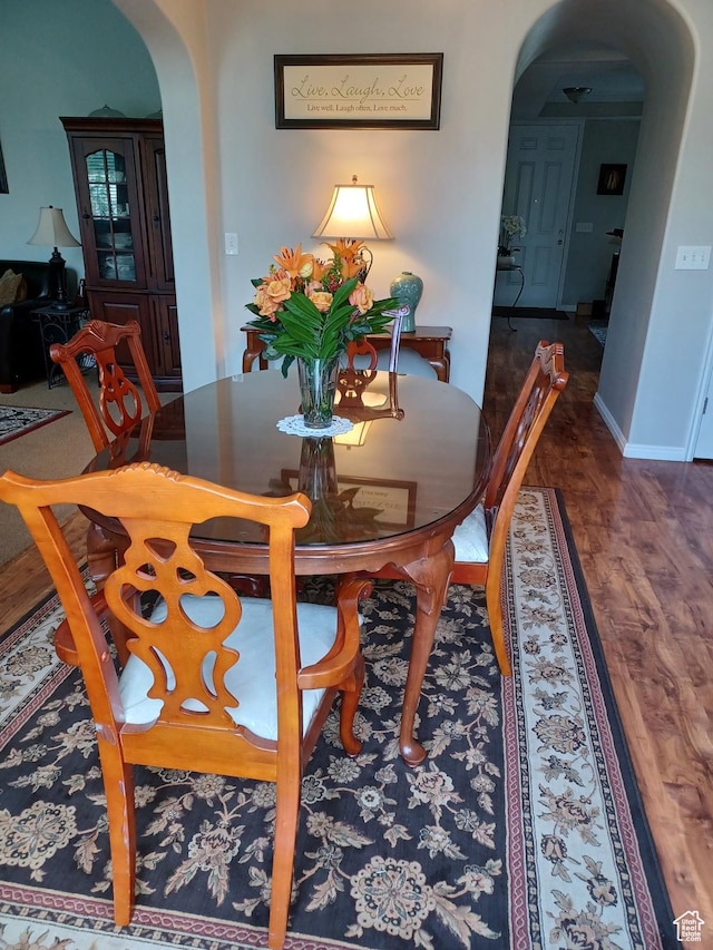 dining area featuring baseboards, arched walkways, and wood finished floors