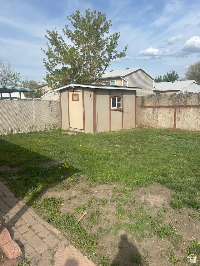view of yard with an outdoor structure, a fenced backyard, and a storage shed