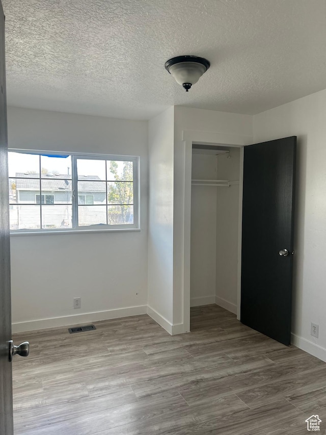 unfurnished bedroom featuring a closet, visible vents, wood finished floors, and baseboards