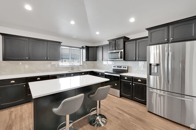 614 S Woodruff Way, Grantsville, UT 84029 - kitchen with decorative backsplash, a breakfast bar area, light wood-style floors, appliances with stainless steel finishes, and a sink
