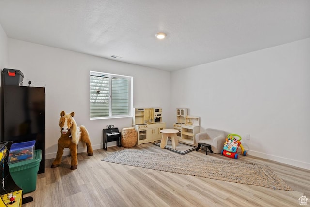 playroom with baseboards, wood finished floors, and visible vents