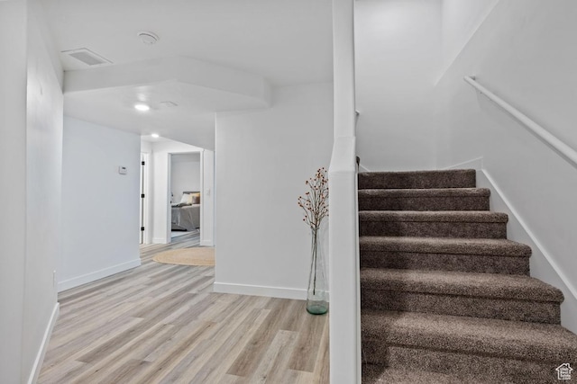 stairway with visible vents, baseboards, and wood finished floors