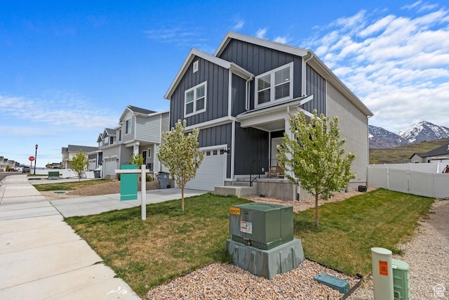 view of front facade featuring fence, a front lawn, concrete driveway, board and batten siding, and an attached garage