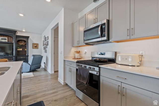 kitchen with open floor plan, gray cabinets, stainless steel appliances, light wood finished floors, and recessed lighting