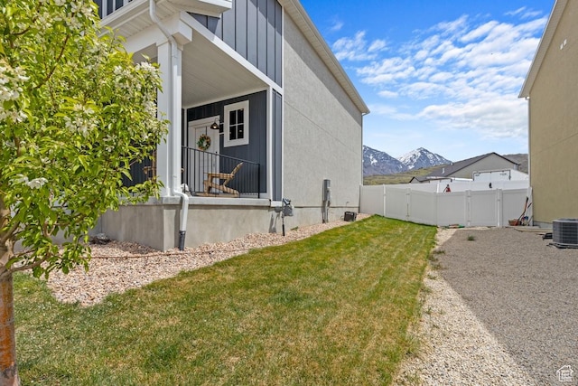 view of side of home featuring a yard, central AC, fence, and a mountain view