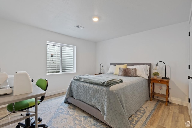 bedroom featuring light wood-style flooring, visible vents, and baseboards