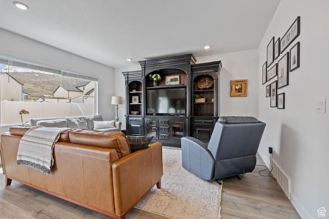 living room with baseboards, wood finished floors, visible vents, and recessed lighting