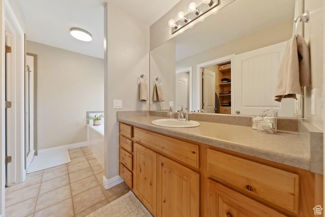 full bathroom featuring tile patterned floors, baseboards, a shower stall, a garden tub, and vanity