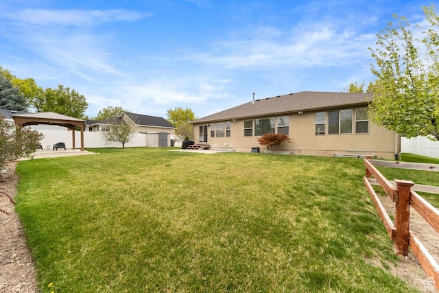 back of property with fence, a yard, stucco siding, a patio area, and a gazebo