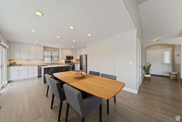 dining area featuring recessed lighting, baseboards, arched walkways, and light wood-style floors