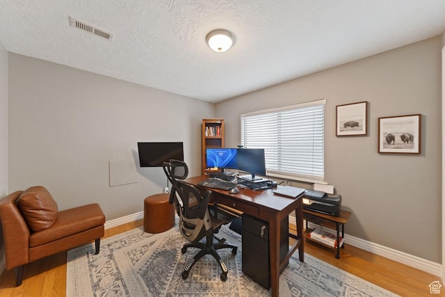 office area with baseboards, wood finished floors, and visible vents