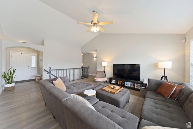 living area featuring lofted ceiling, baseboards, light wood finished floors, and ceiling fan