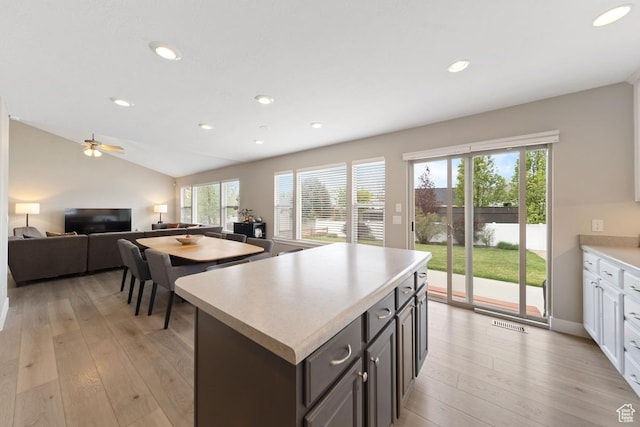 kitchen featuring lofted ceiling, open floor plan, light countertops, and light wood-style floors