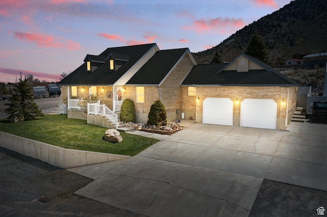 view of front facade with a front lawn, a mountain view, driveway, brick siding, and an attached garage