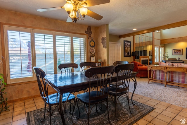 2548 E Cobblestone Way, Sandy, UT 84093 - dining room featuring light tile patterned floors, ceiling fan, a textured ceiling, a fireplace, and light carpet
