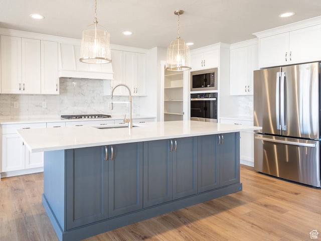 2552 W 2950 N Unit 119, Farr West, UT 84404 - kitchen featuring a kitchen island with sink, backsplash, light countertops, white cabinets, and appliances with stainless steel finishes