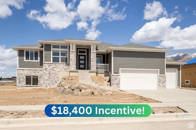 prairie-style home with a garage, driveway, and stone siding