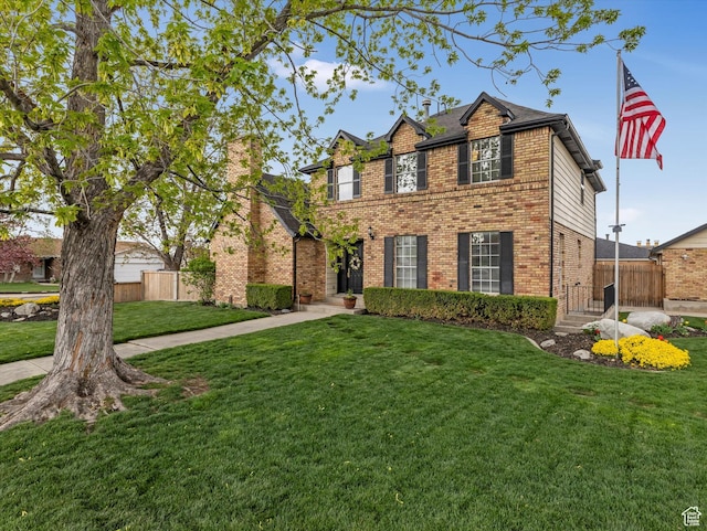 traditional-style home featuring brick siding, fence, and a front lawn