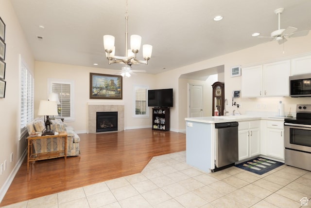 7170 S 420 E, Midvale, UT 84047 - kitchen featuring appliances with stainless steel finishes, a tiled fireplace, light wood finished floors, and ceiling fan with notable chandelier