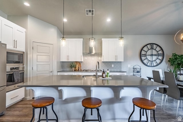 658 N Sage Crest Dr, Washington, UT 84780 - kitchen featuring wall chimney range hood, visible vents, stainless steel appliances, dark countertops, and backsplash